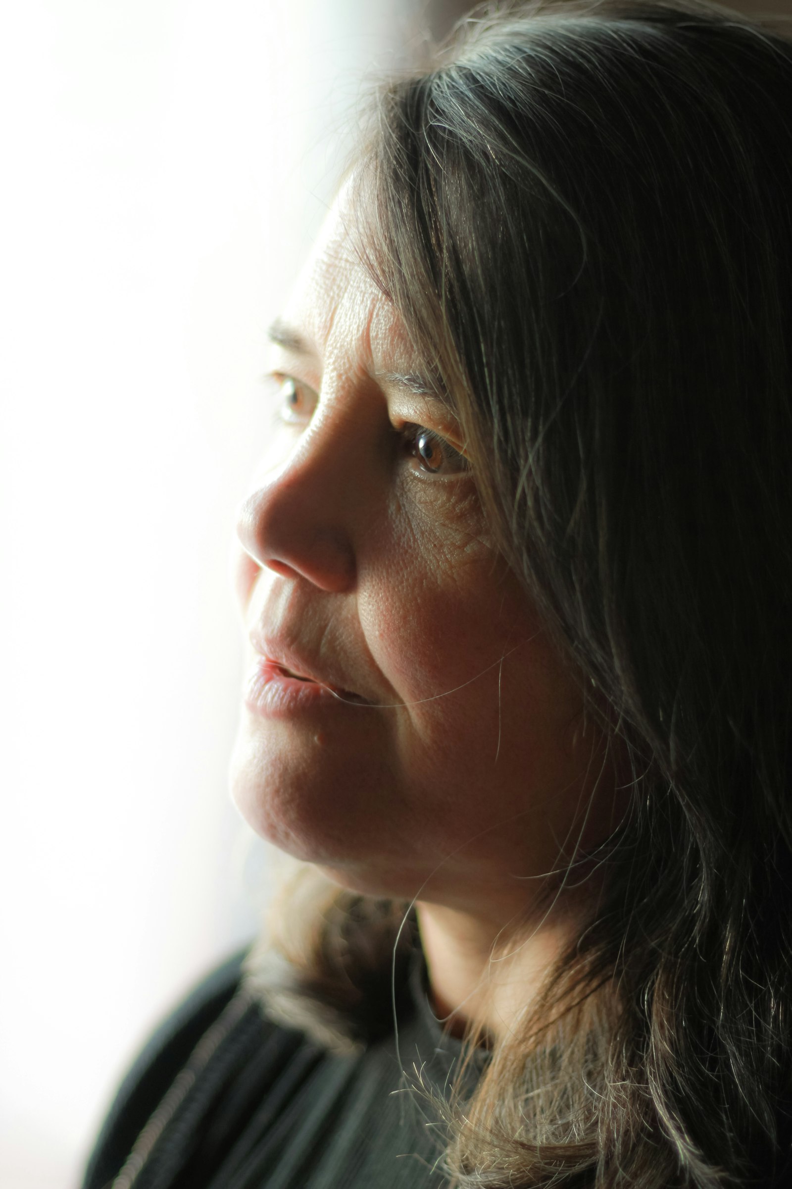 Woman reflecting by a window in warm light